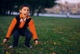 boy outside in autumn jumping an dscreaming