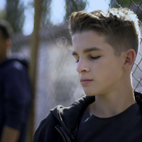 boy in front of wired bars