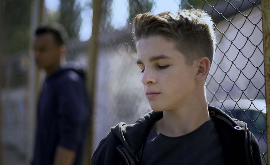 boy in front of wired bars
