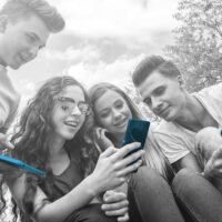 Group of friends sitting together using their mobile phones