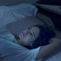 teenage boy suffering from insomnia lying in bed at night.