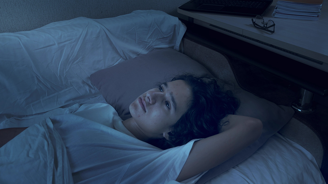 teenage boy suffering from insomnia lying in bed at night.
