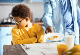 Fussy eater. Pouting pre-teen boy sitting at the table and turning away while refusing to eat a fried egg