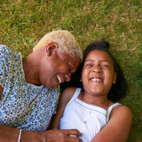 Black girl and grandmother lying on grass, overhead close up