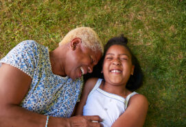 Black girl and grandmother lying on grass, overhead close up