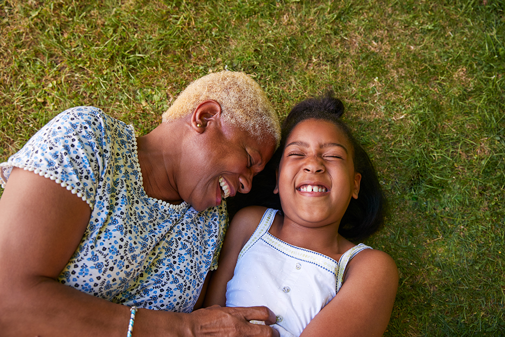 Black girl and grandmother lying on grass, overhead close up