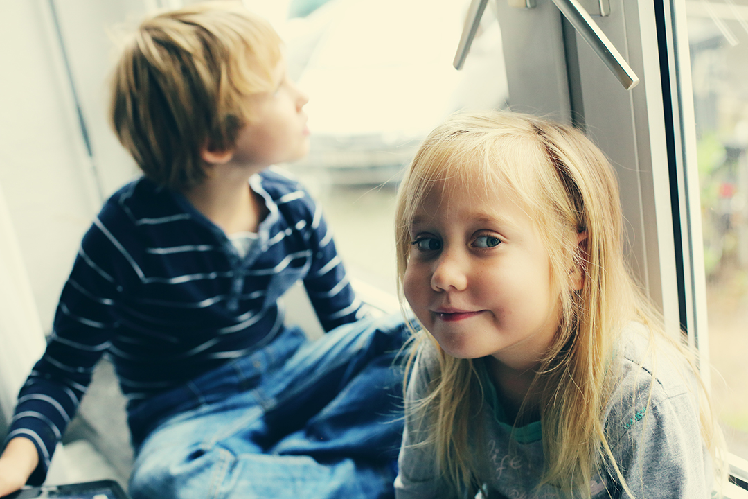 Sister and brother are sitting near the window
