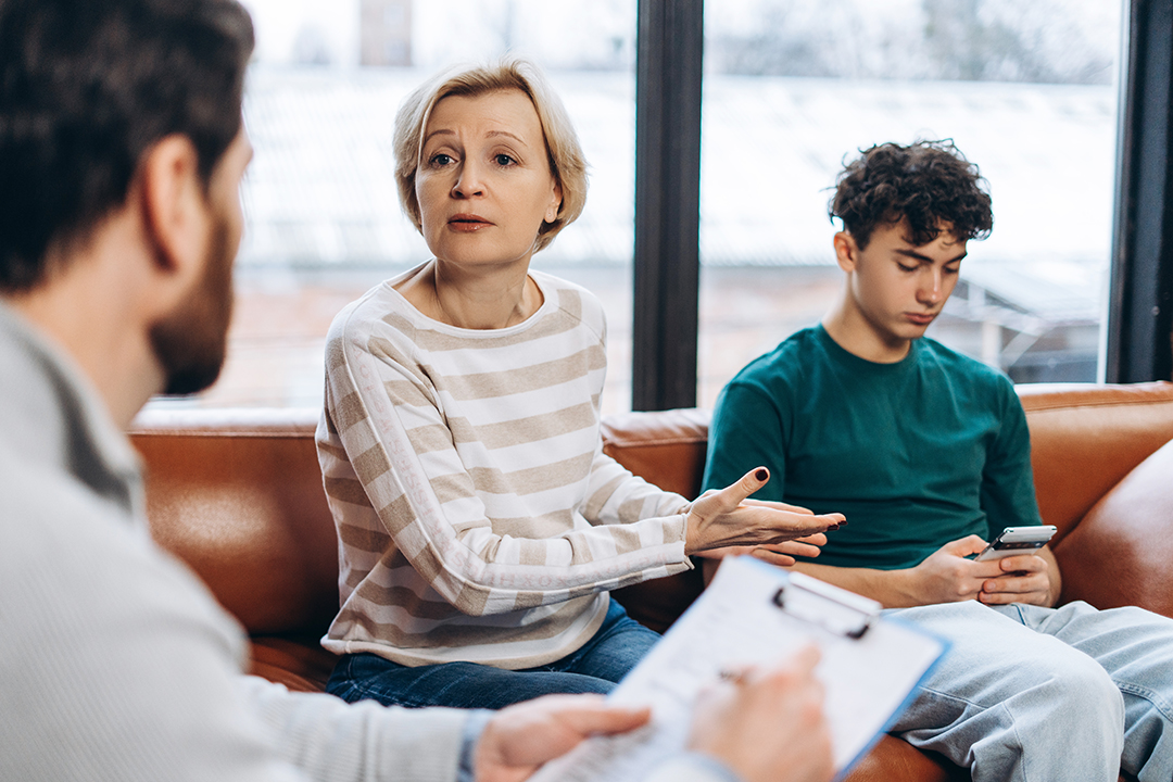 Portrait of mother talking to male psychologist about her teenage boy and phone addiction. Counseling therapy. Psychology treatment