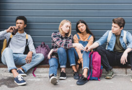 teenagers sitting, drinking beer from glass bottle and holding cigarette