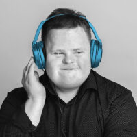 Intellectual disability boy smiling listing to music on wrap headphones