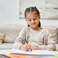 young girl drawing at a desk