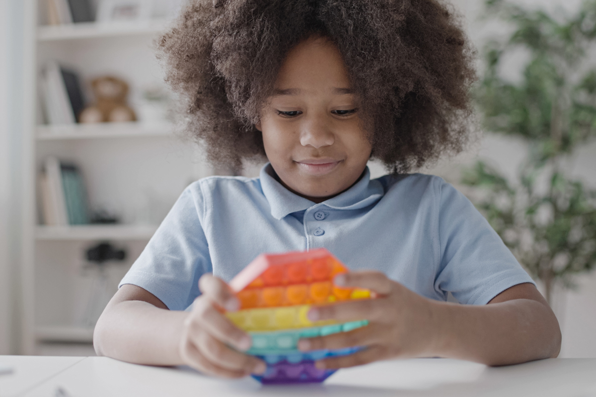 African American girl playing with pop it toy, pressing buttons, stress relief