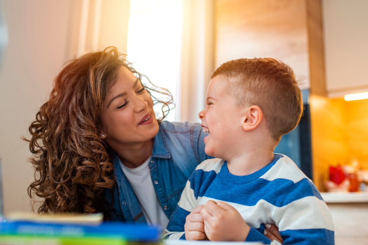 Kind mother helping her son doing homework in kitchen. Children's creativity. Portrait of smiling mother helping son with homework in kitchen at home