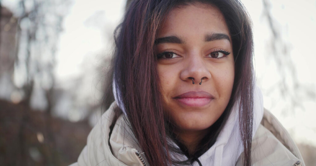 Close-up portrait of multi-race beautiful young woman looking into camera. Teenage girl with piercing in nose.