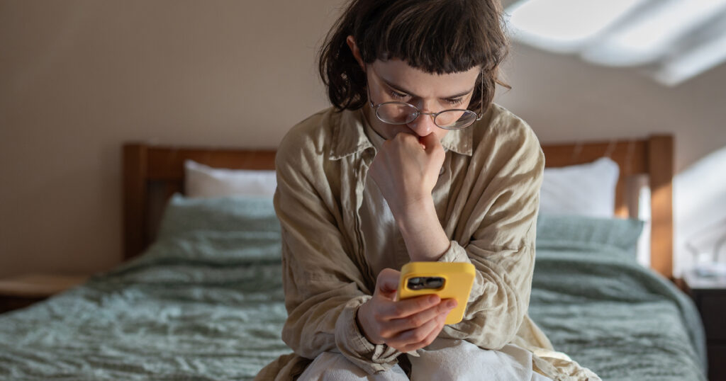 Nervous, stressed teen girl in glasses reading messages in smartphone feeling bad, humiliated. Depressed frustrated woman receive negative message in social media from haters. Cyberbullying, stalking.
