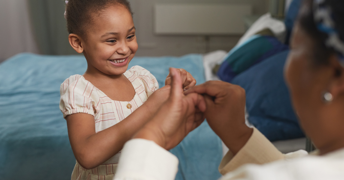 African-American girl playing with grandmother and laughing happily in cozy home setting