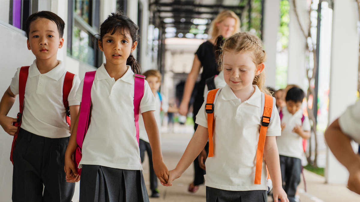 Primary School Students Wearing Uniform walking in outdoor hallway going to class