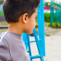 dark haired boy swinging on a swing