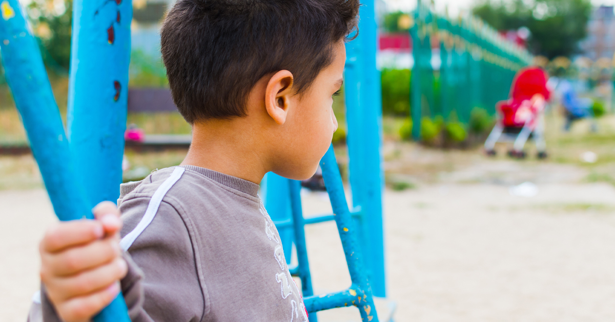 dark-haired boy swinging on a swing