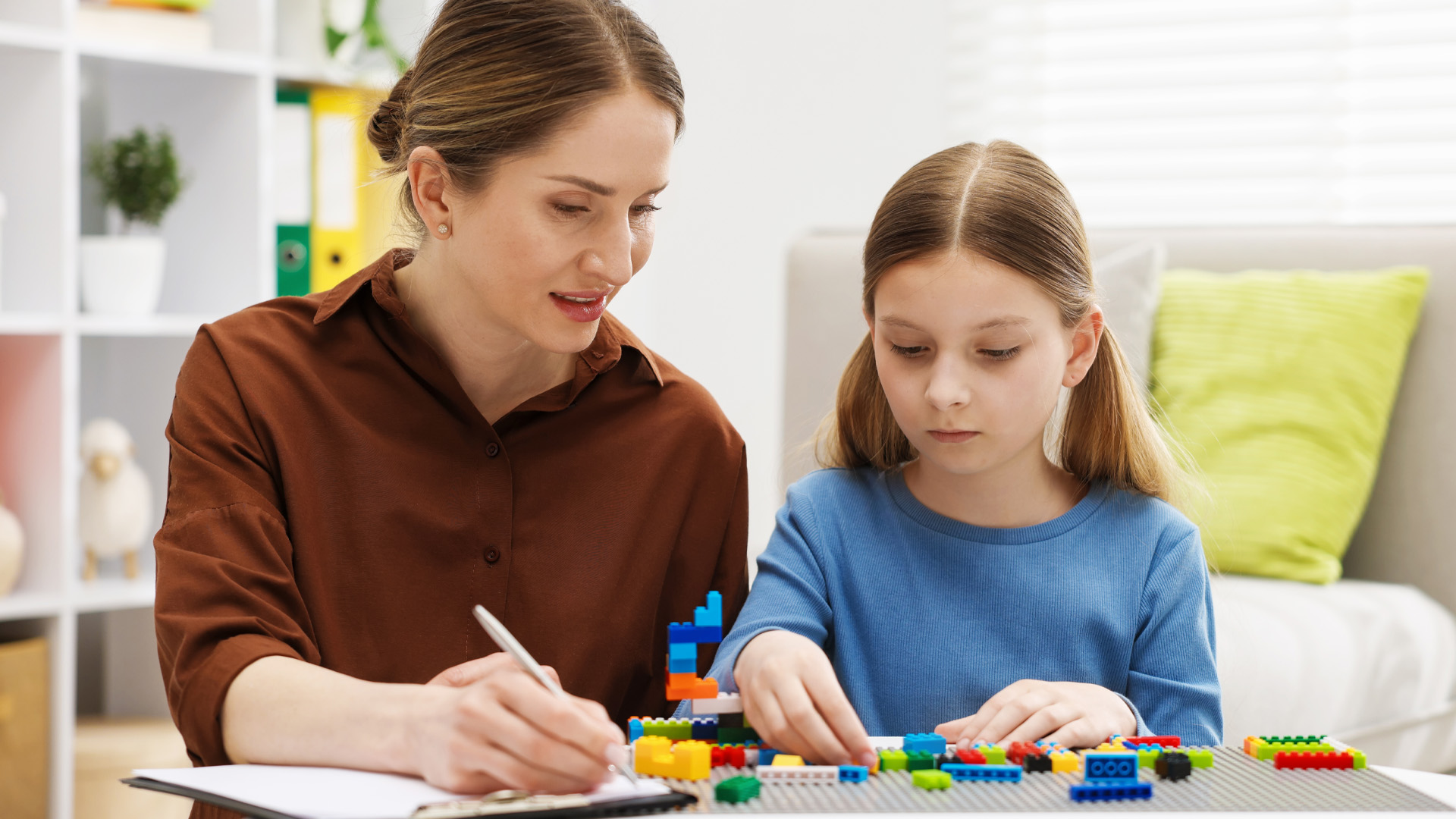 Girl playing with toys at white table during consultation with professional child psychologist indoors Girl playing with toys at white table during consultation with professional child psychologist indoors
