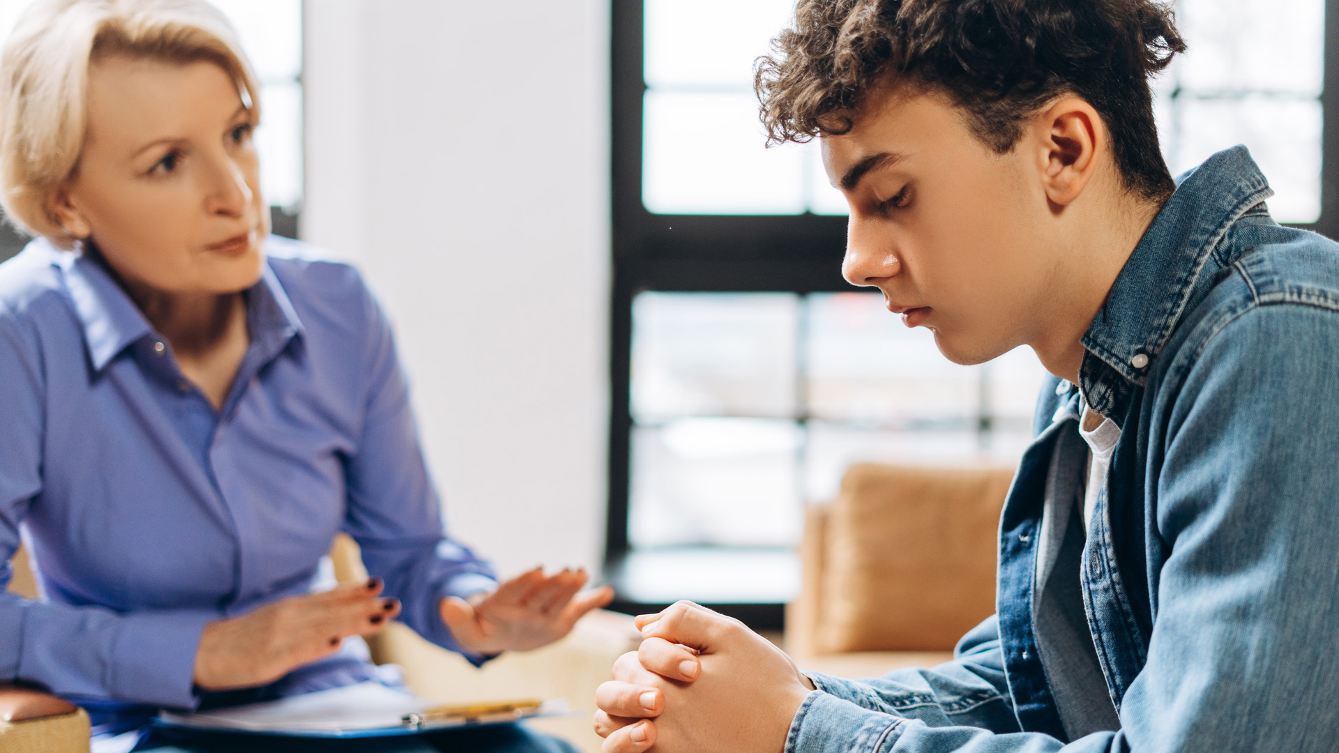 Portrait of professional female psychologist working with teenager boy in office while explaining. Portrait of professional female psychologist working with teenager boy in office while explaining.