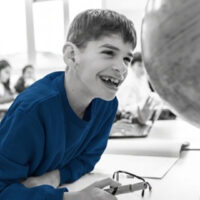 happy student with SEND smiling while exploring a globe in geography class, showcasing inclusive education and learning