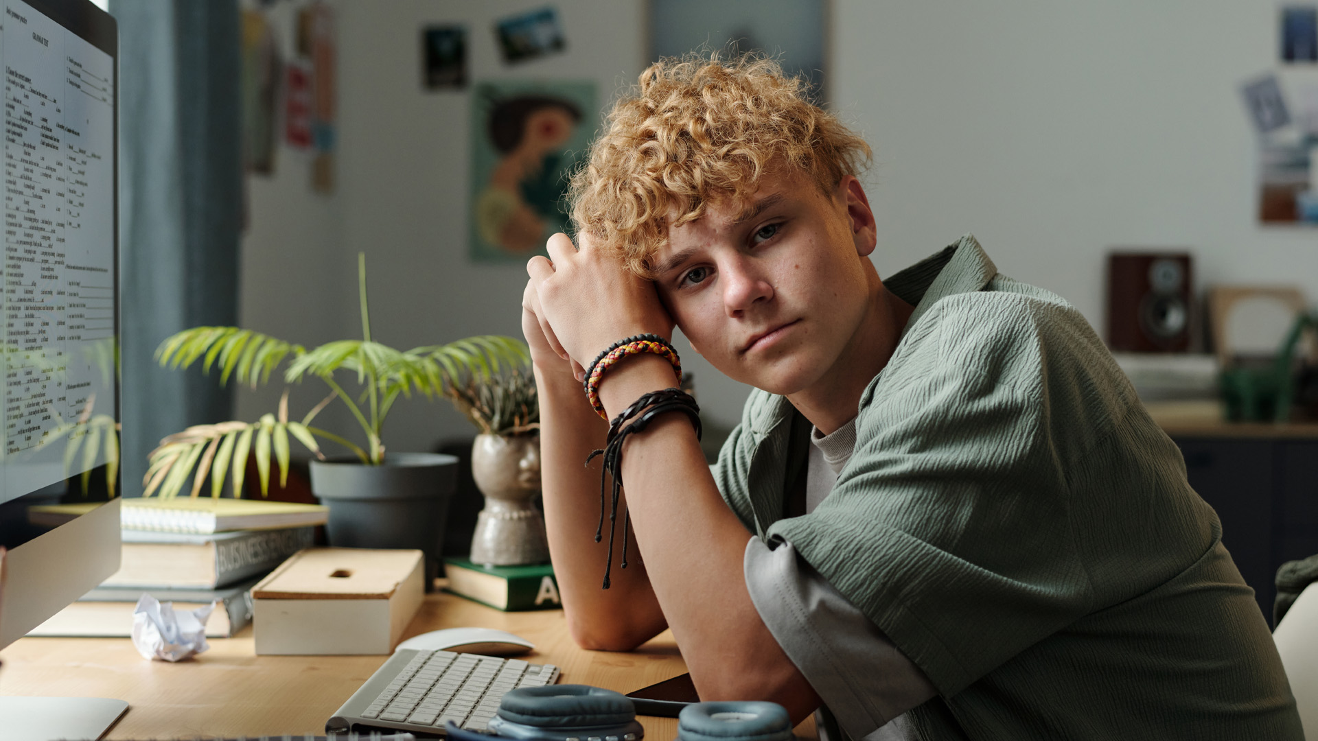 important life events for teens_teen boy at computer teenage boy sitting at desk leaning on arm