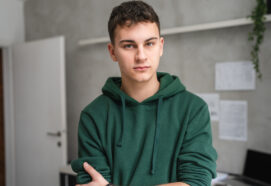 teenage boy stood in room at home wear green hoodie