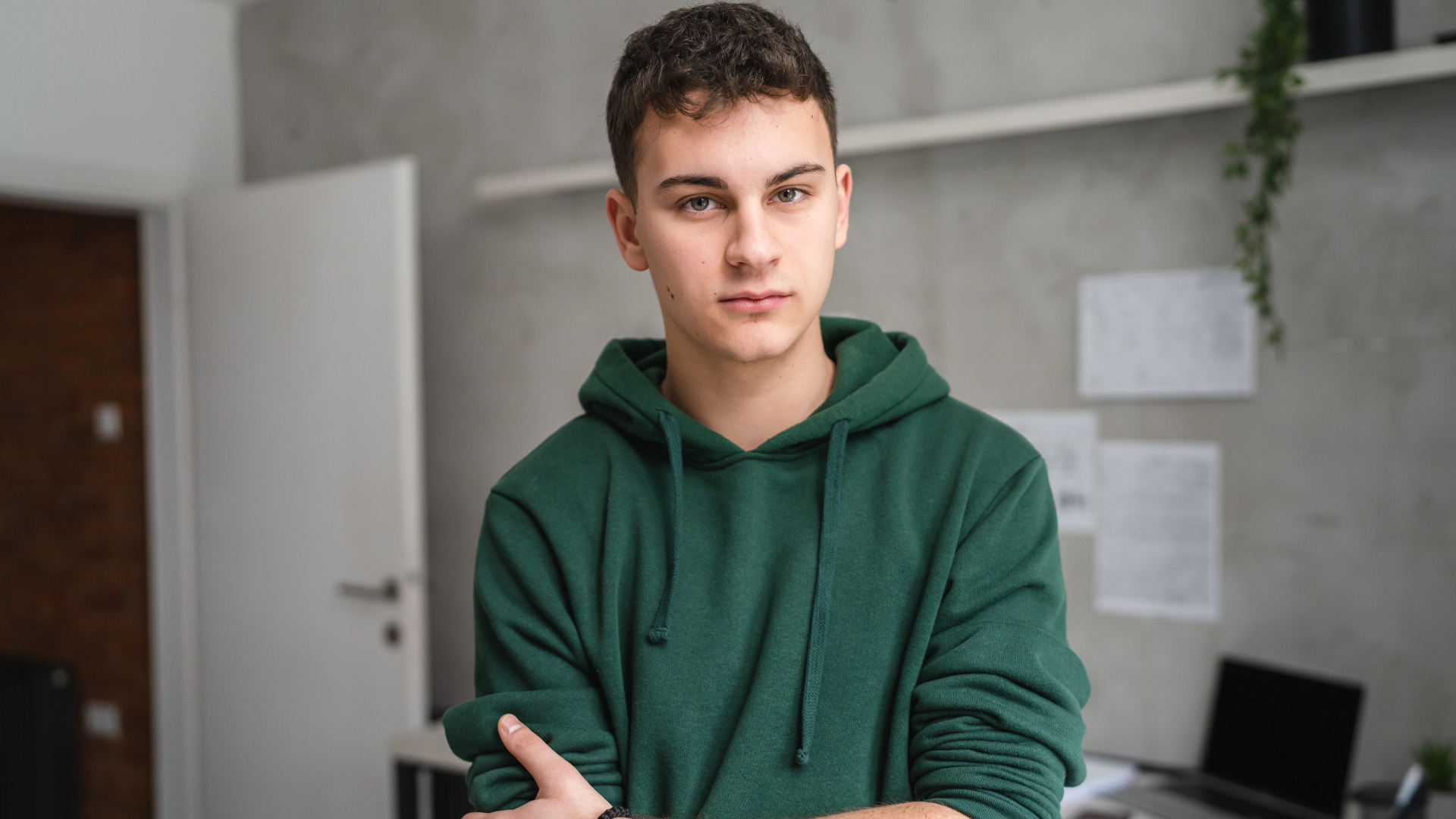 teenage boy stood in room at home wear green hoodie teenage boy stood in room at home wear green hoodie
