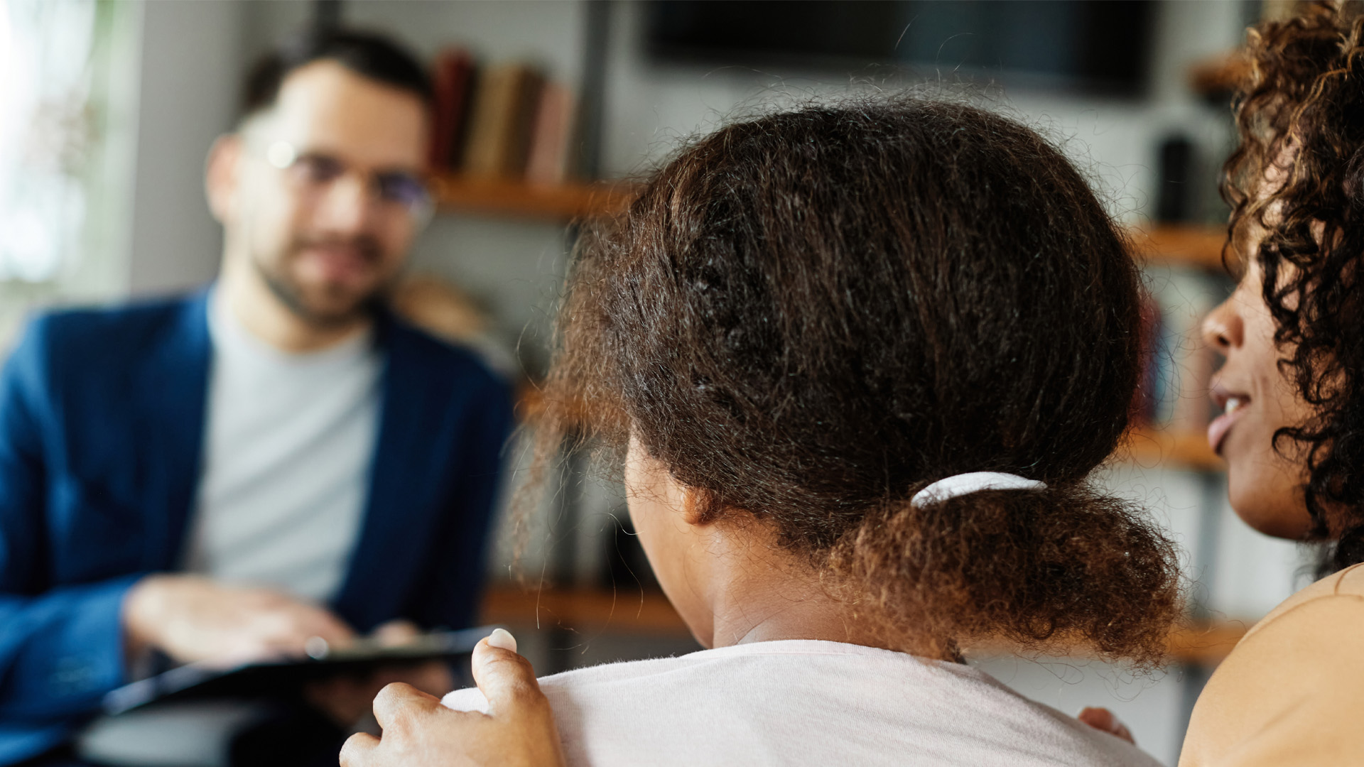 Mother with her teenage daughter at meeting with psychologist discussing mental health sitting on sofa in psychotherapist office Mother with her teenage daughter at meeting with psychologist discussing mental health sitting on sofa in psychotherapist office