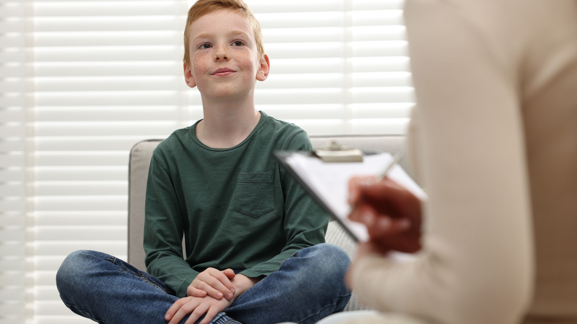 Professional child psychologist working with boy on sofa indoors Professional child psychologist working with boy on sofa indoors
