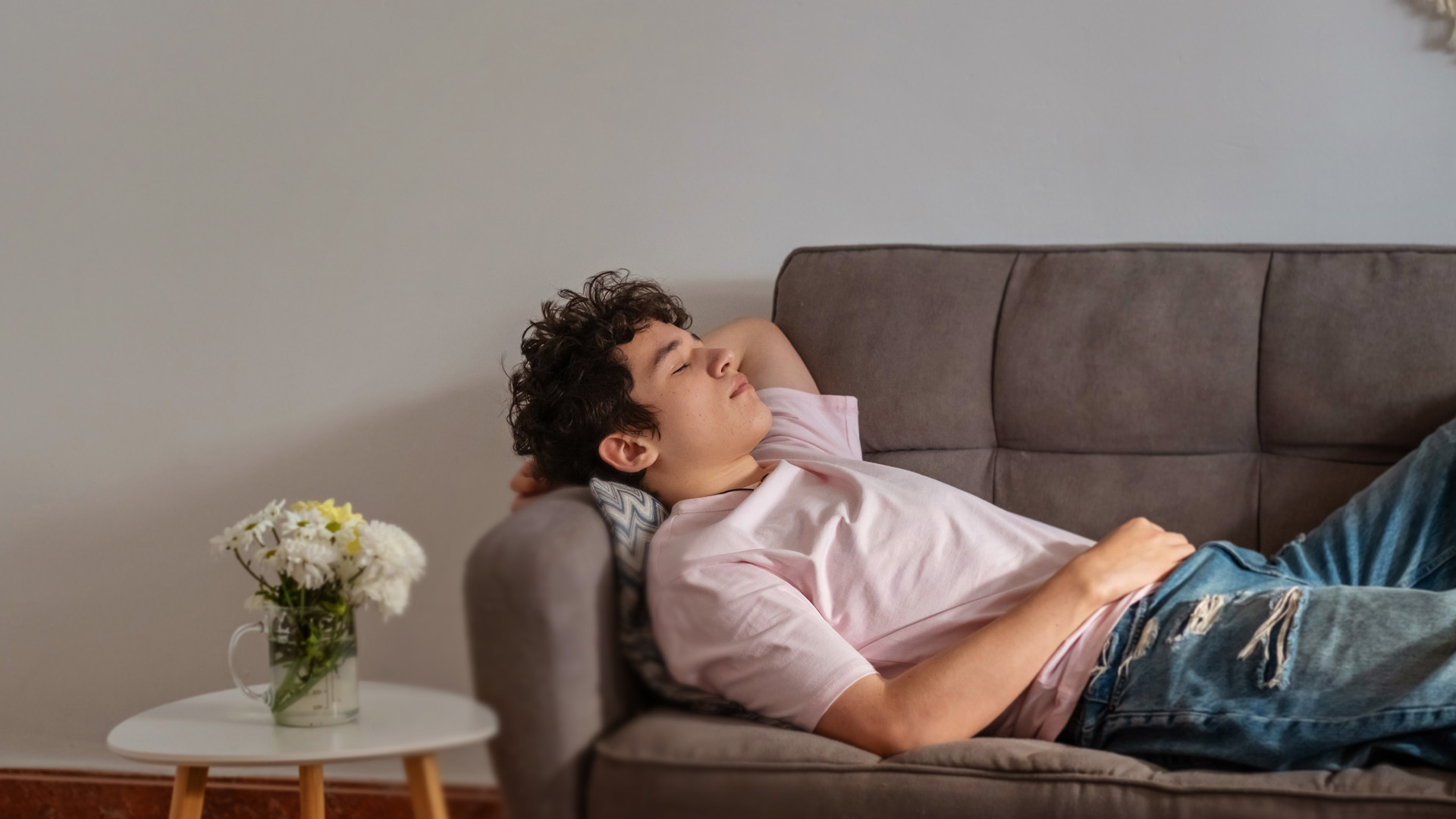 Teenage boy falls asleep on the sofa in the middle of the day with his head thrown back Teenage boy falls asleep on the sofa in the middle of the day with his head thrown back